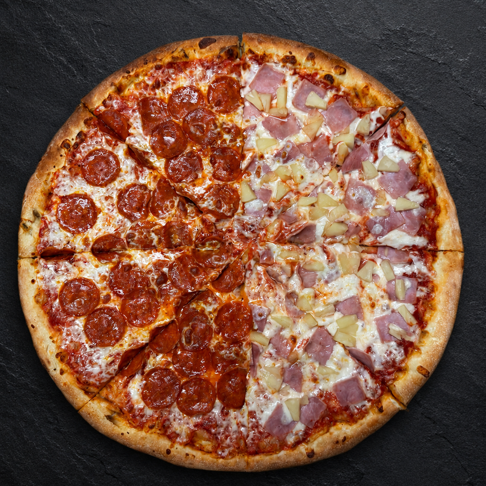 A whole pizza, half pepperoni and half ham and pineapple, on a dark textured surface.