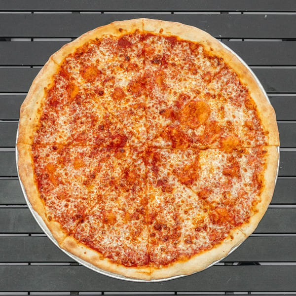 A whole cheese pizza, cut into eight slices, on a dark gray slatted table.